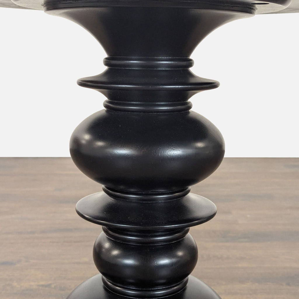 3. Close-up of the Reperch end table’s sculpted black pedestal, featuring rounded and flared details.