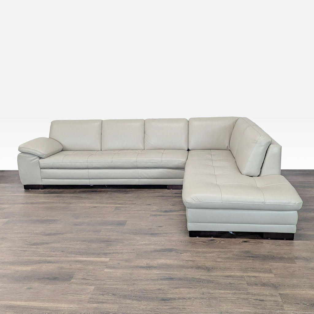 Modern L-shaped Scandinavian Designs sectional in light gray leather, featuring wide armrests and plush cushions.