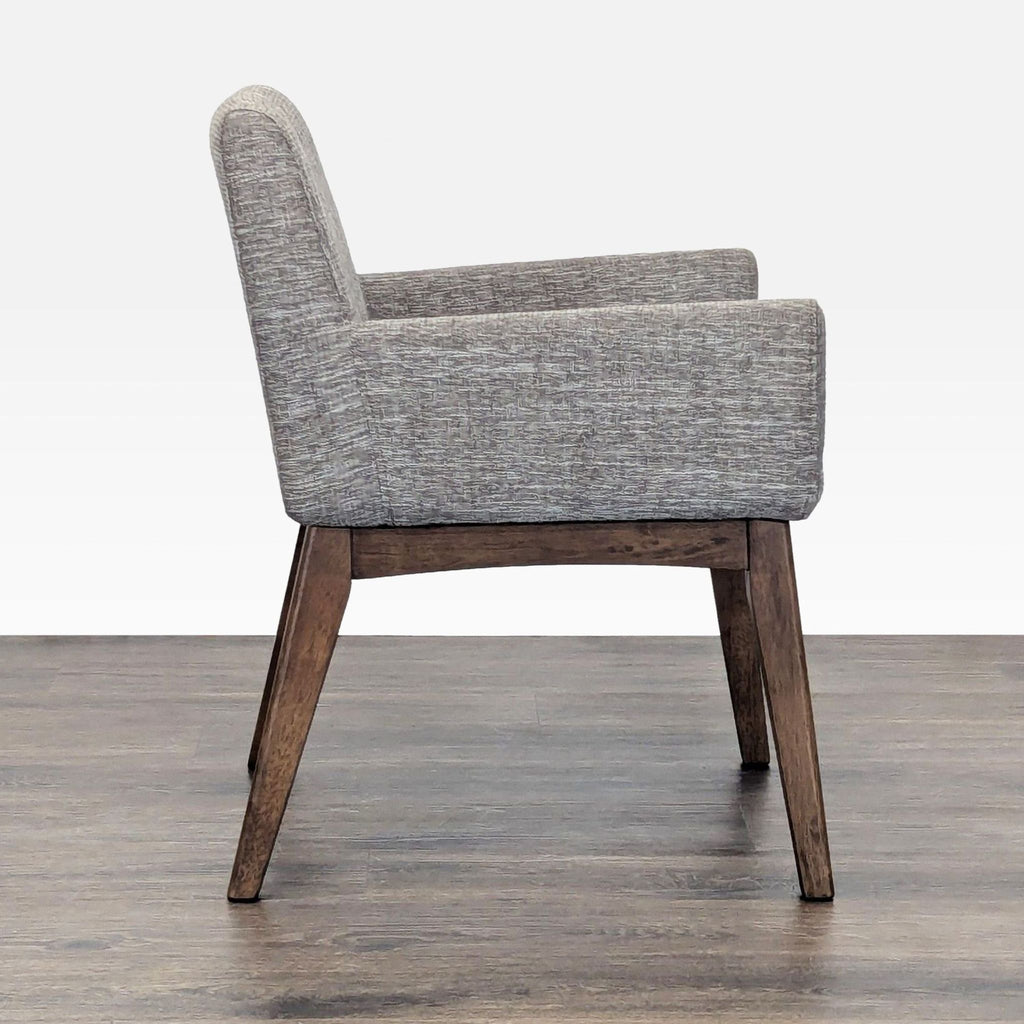 Side view of the Article lounge chair, showing its sleek armrests and cushioned seat on a wooden frame.