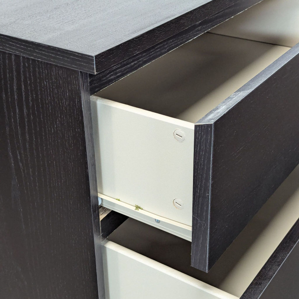 - Close-up of IKEA black dresser drawer, showing sturdy construction and smooth interior for organized storage.