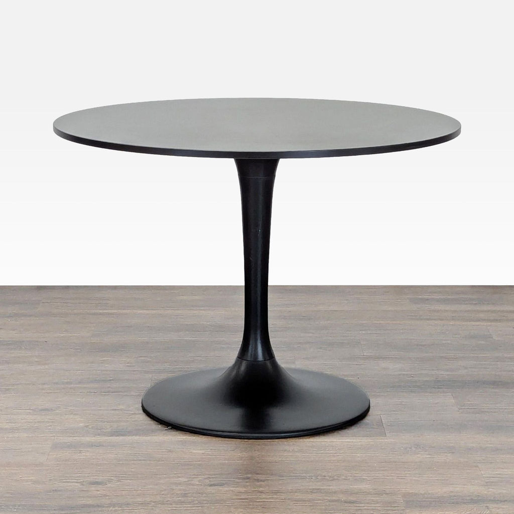 1. Round black Ikea dining table with a laminate top and powder-coated steel base, shown on a wood floor.  