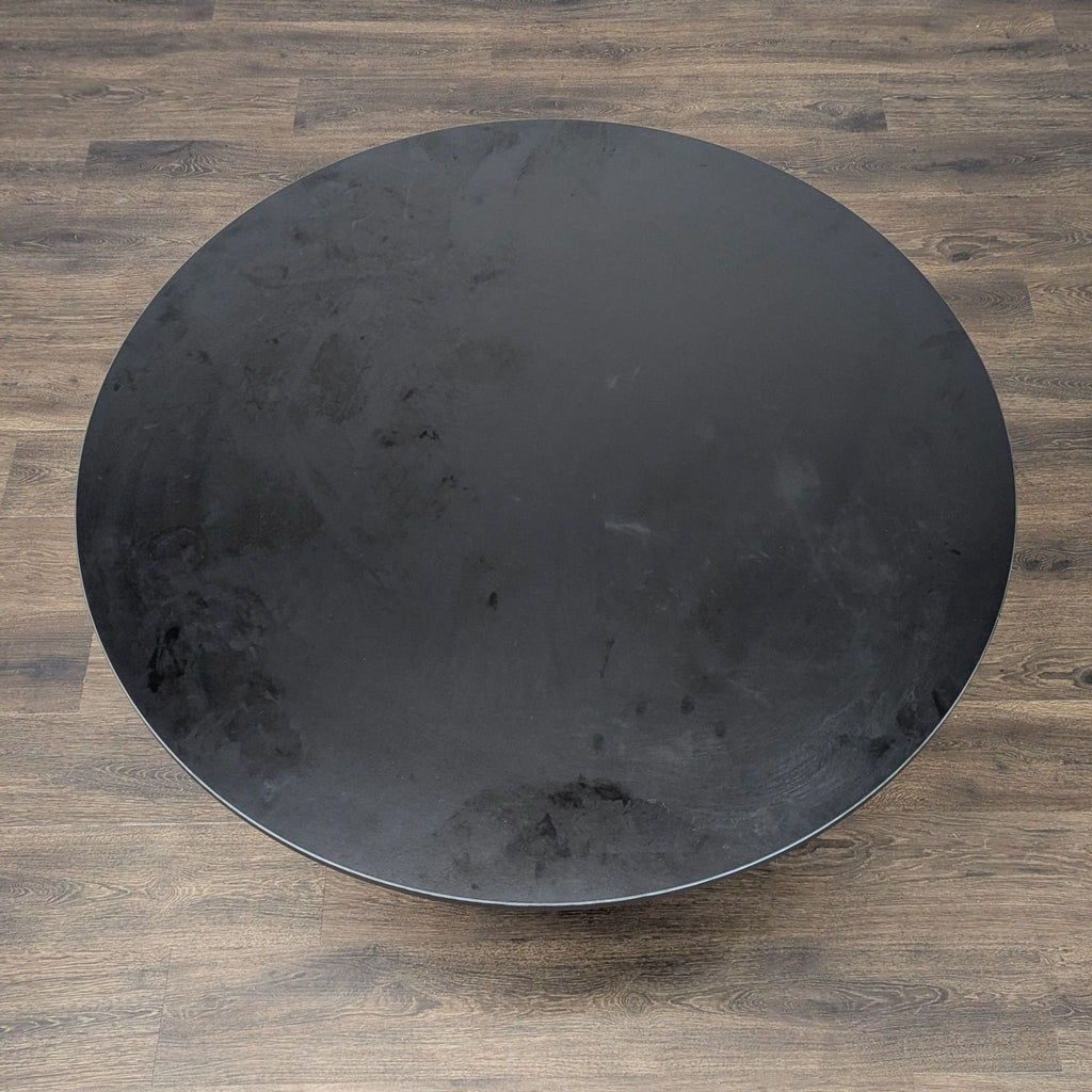 2. Top view of a round black particleboard dining table from Ikea, with a smooth laminate finish.  
