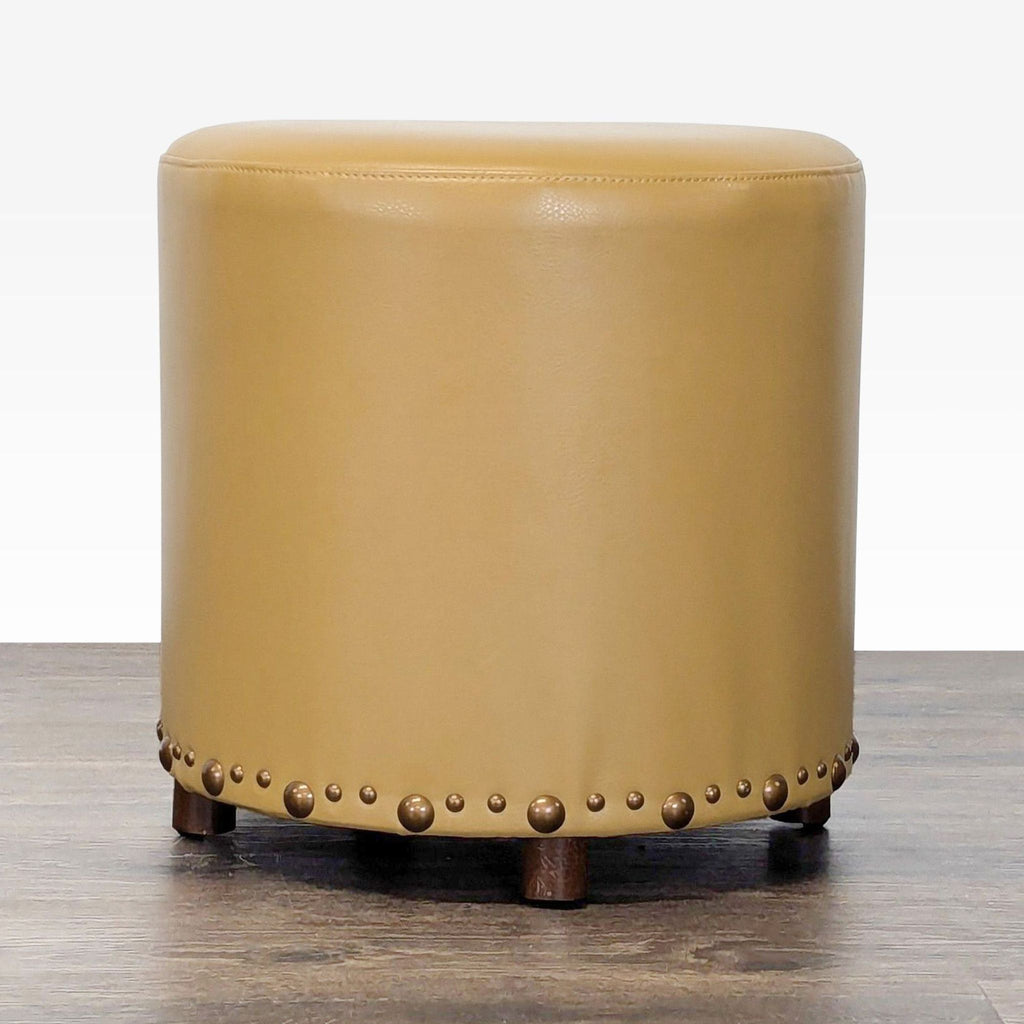 1. Round tan leather ottoman with brass nailhead trim and short wooden legs, from Reperch's Stools collection.