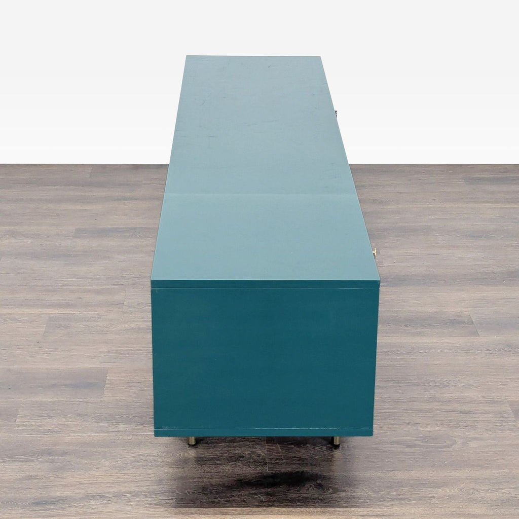 3. Side view of the Anthropologie entertainment center, highlighting its sleek teal veneer and brass legs.