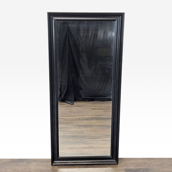 1. Ikea mirror with a rectangular wood frame, shown standing upright on a wooden floor with black drapery reflected.  
