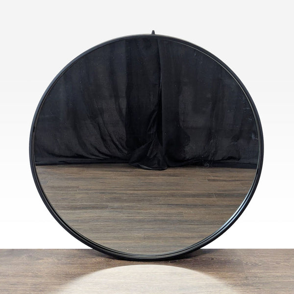 1. Round Reperch mirror with a black metal frame, reflecting wooden floor and dark fabric backdrop.