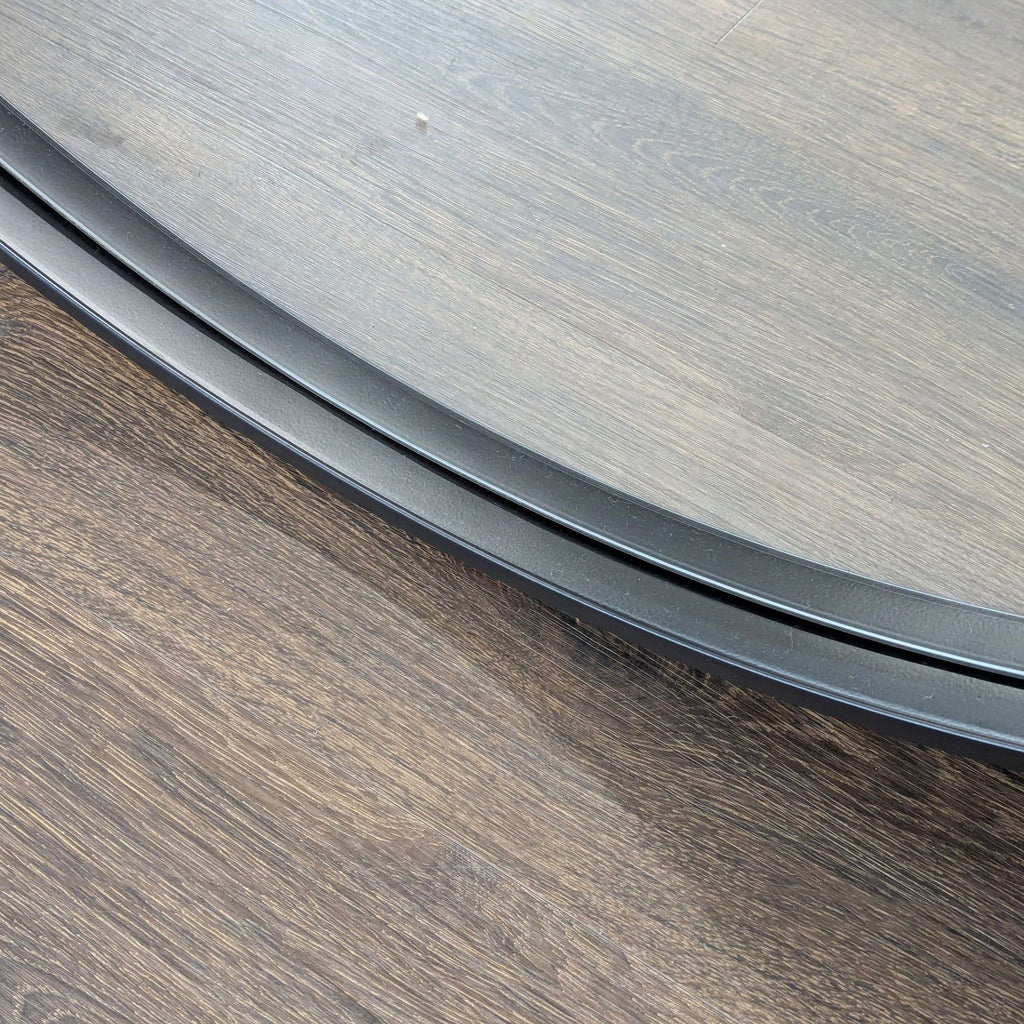 2. Close-up of the Reperch mirror’s matte black edge placed on a wooden surface.