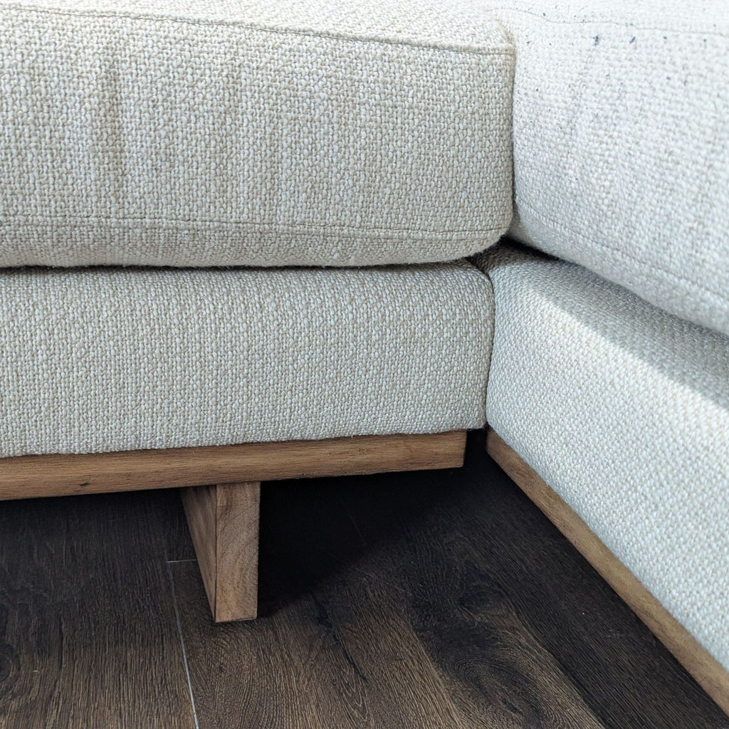3. Close-up of textured beige sectional and its sturdy wood base, showing detailed fabric and construction.