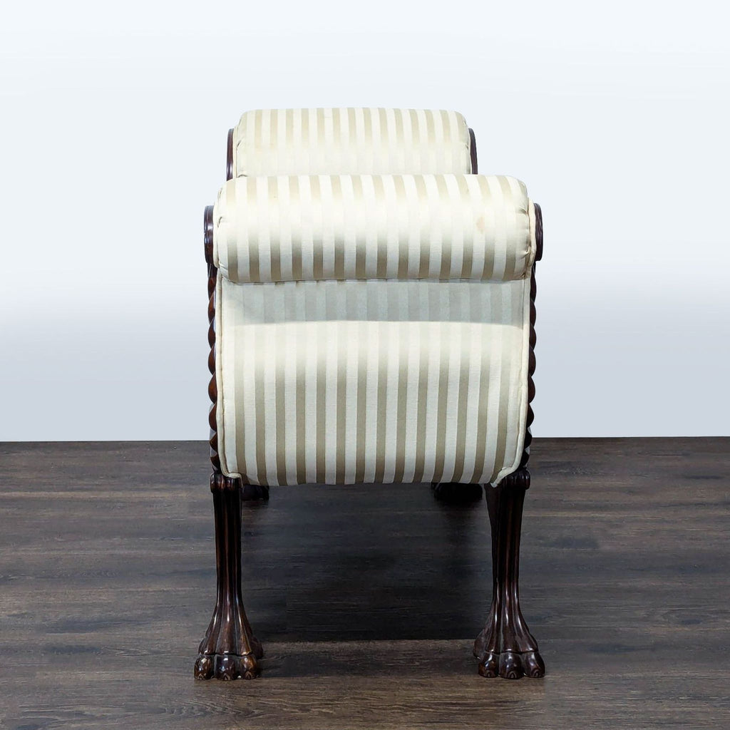 3. End view of a Reperch ottoman with clawed feet and striped cushioned sides in elegant cream tones.