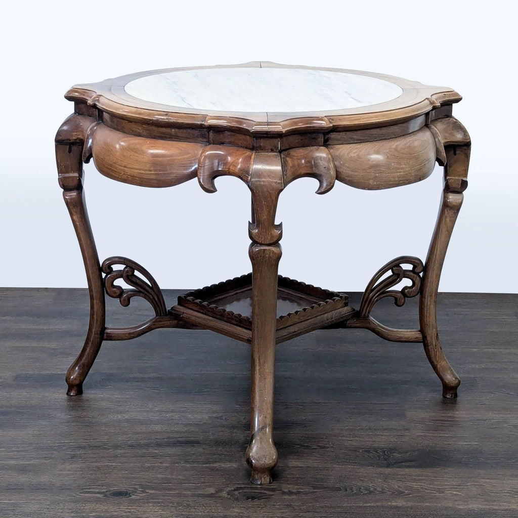 2. Reperch brand end table featuring curved legs, a marble top, and intricate woodwork on the structure and shelf.  