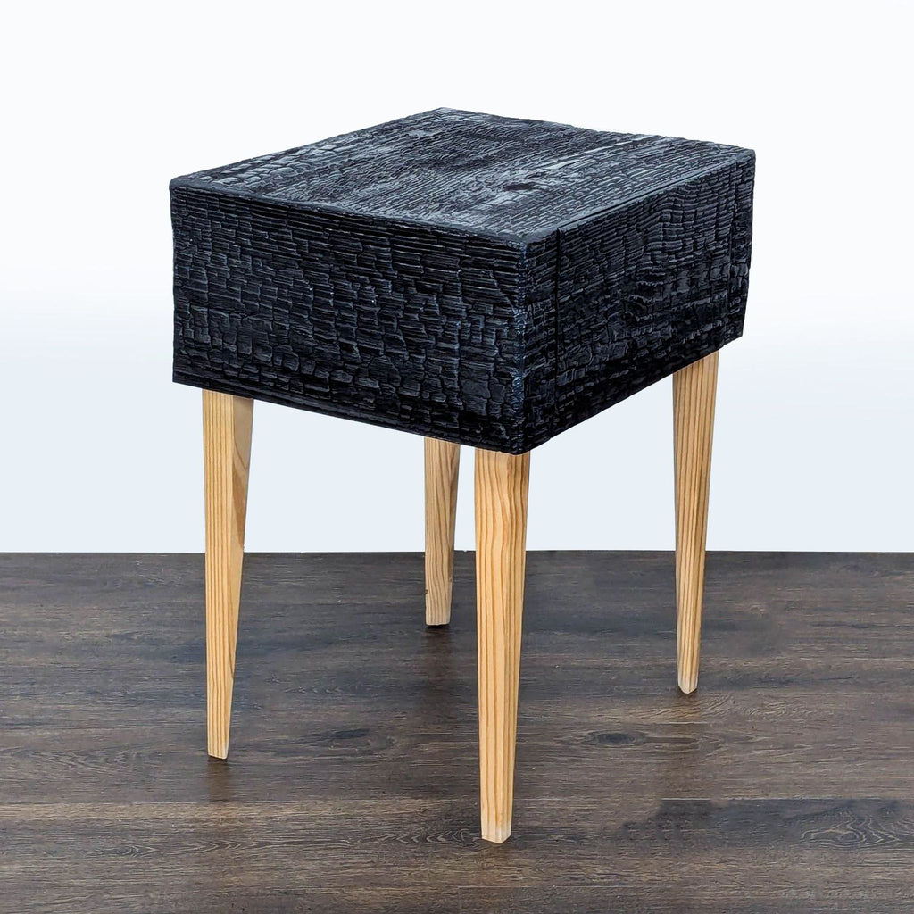 A contemporary single-drawer end table with dark, charred wood and smooth, mitered edges, inspired by Japanese techniques.