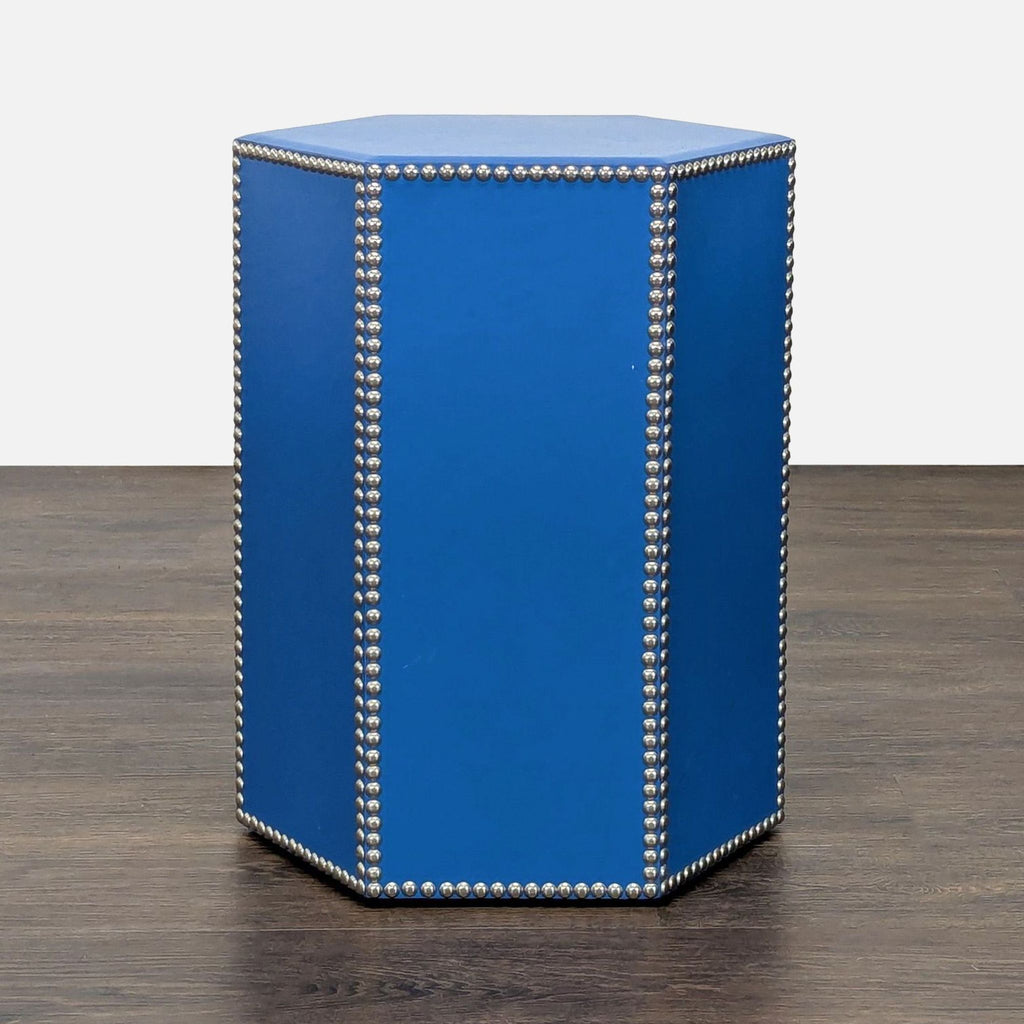 Hexagonal cobalt blue leather stool with nickel stud trim, shown on a dark wood floor.  