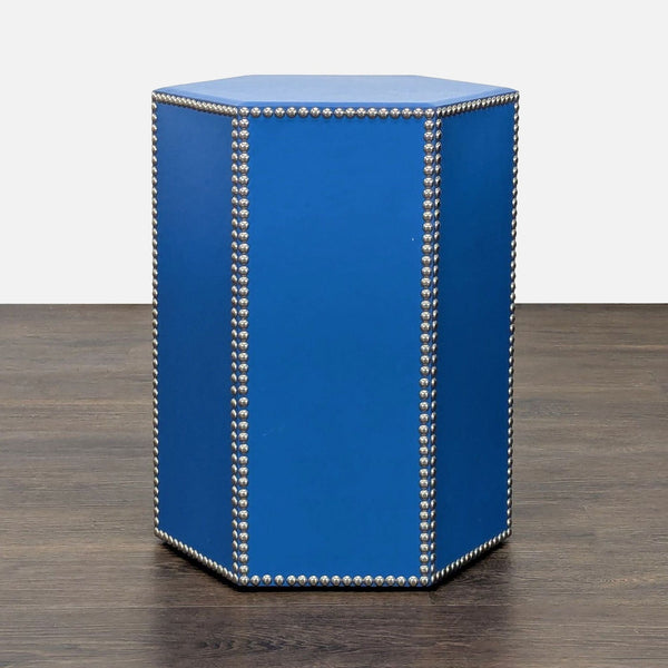 Hexagonal cobalt blue leather stool with nickel stud trim, shown on a dark wood floor.  