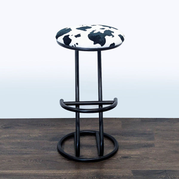 1. Modern Reperch stool with cow print seat and black metal frame, shown on a dark wooden floor.