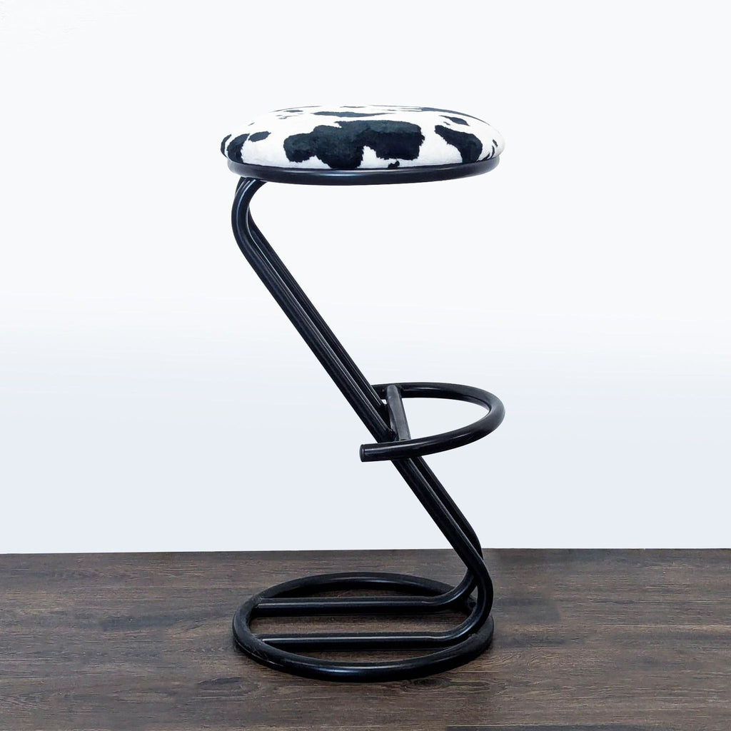 3. Contemporary black metal stool by Reperch, with circular base and eye-catching cow print upholstery.