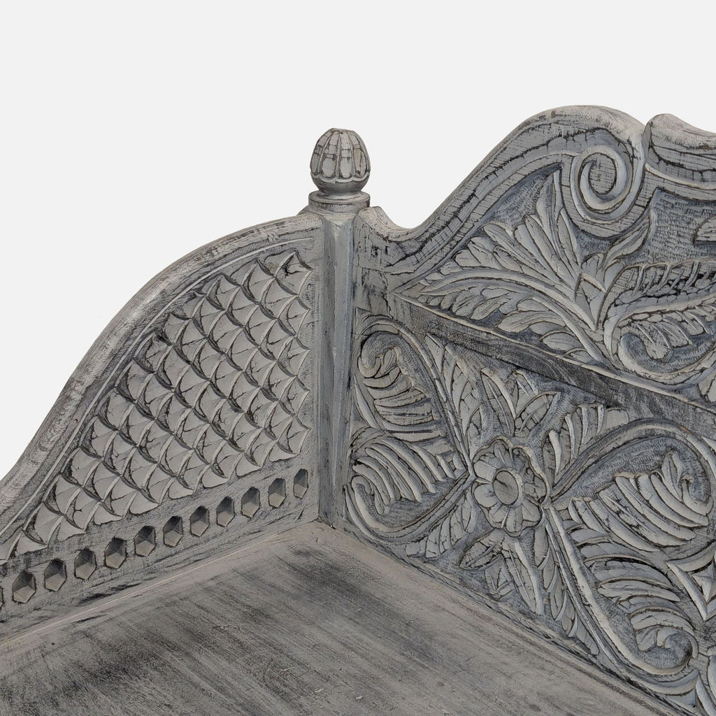 2. Detailed view of ornate floral and geometric carvings on a gray-white Living Spaces bench corner.