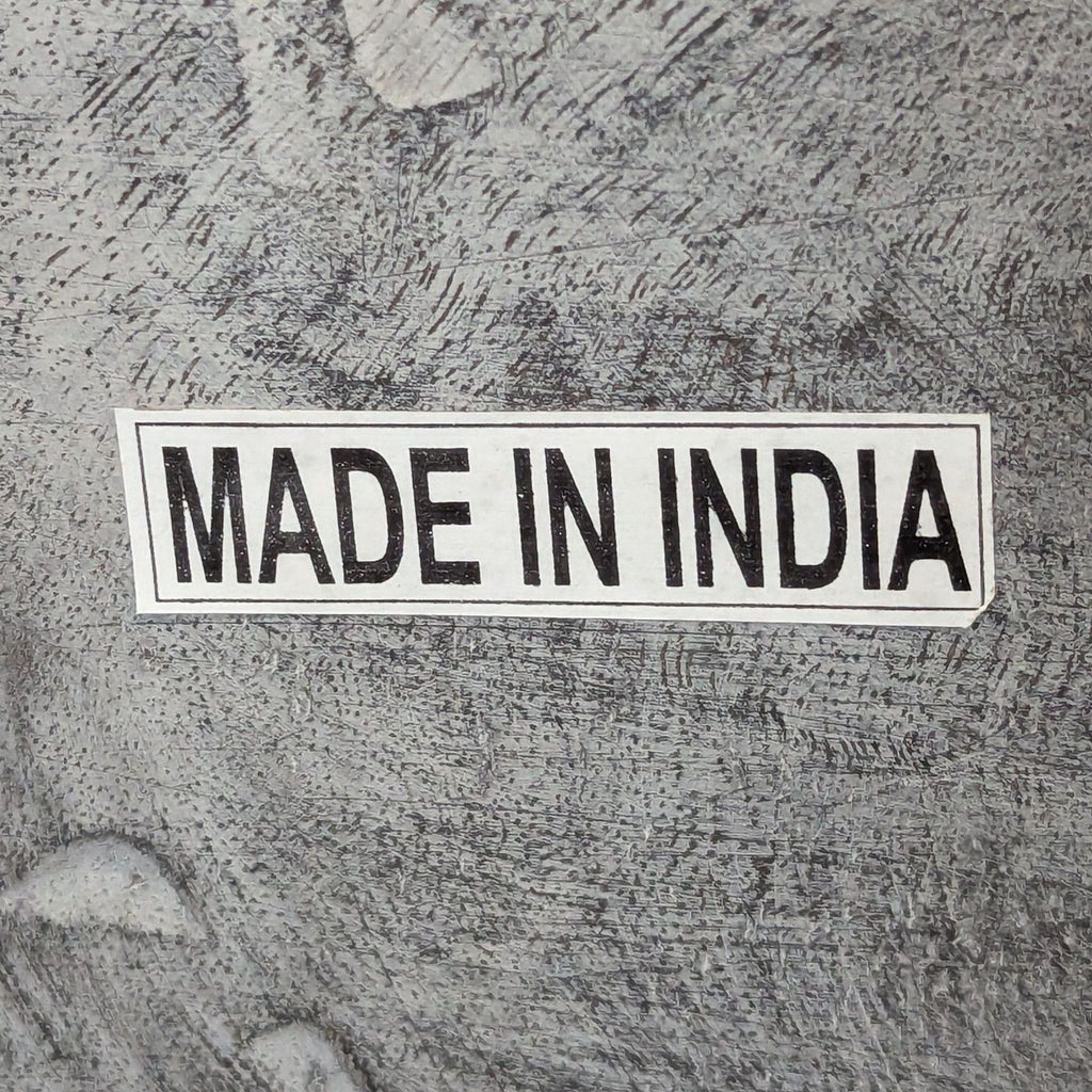3. "Made in India" label on a textured gray wood surface of a Living Spaces bench.