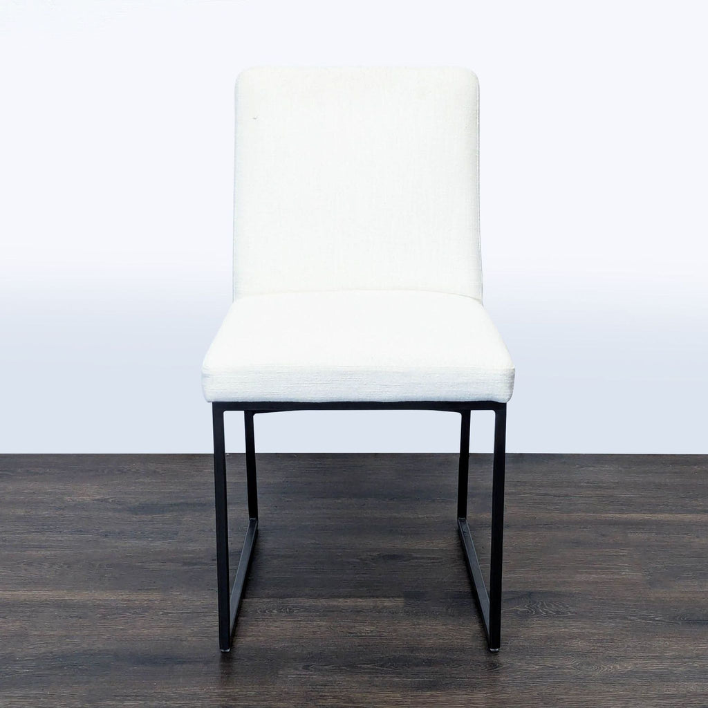 1. West Elm dining chair with a dark bronze frame and white upholstery, shown from the front on a wooden floor.  
