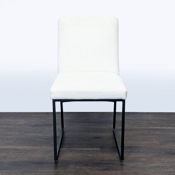 1. West Elm dining chair with a dark bronze frame and white upholstery, shown from the front on a wooden floor.  