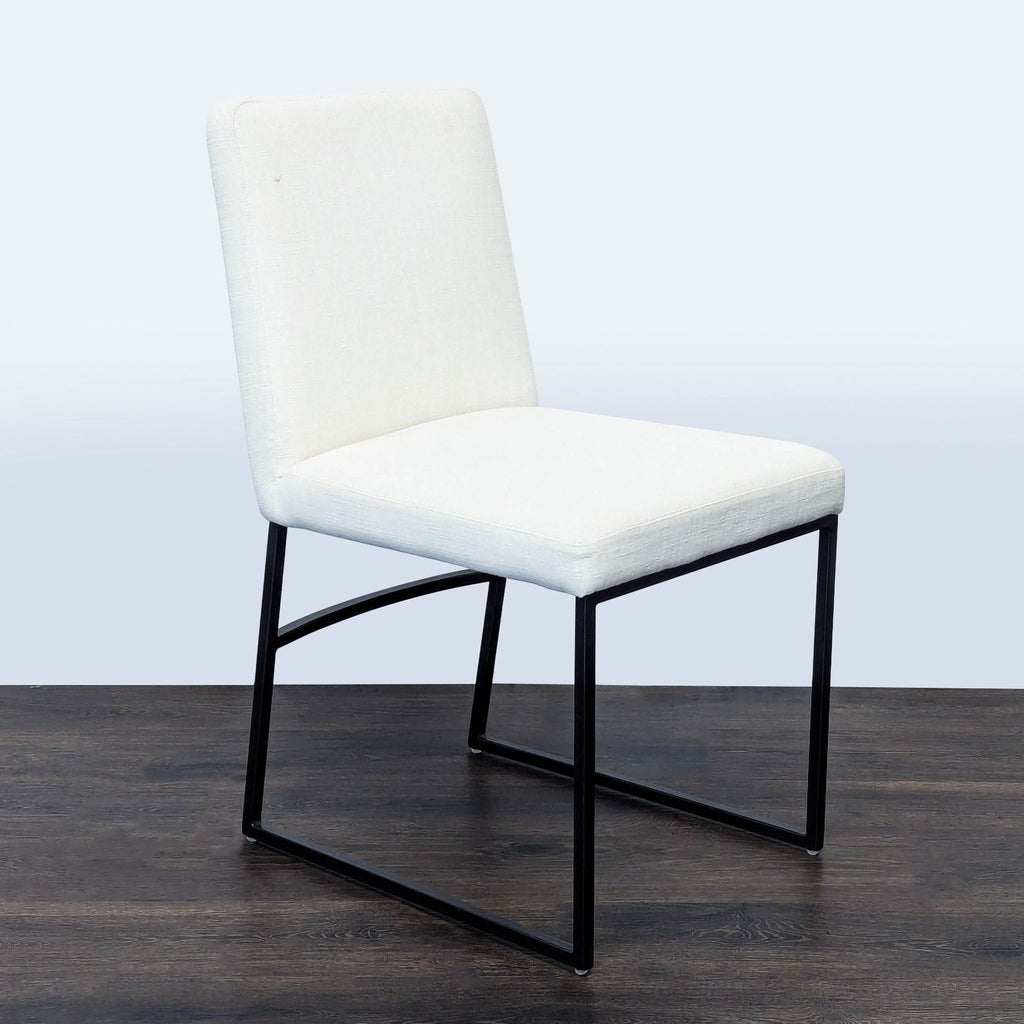 2. Modern West Elm dining chair featuring white cushioning and a sleek dark bronze finish frame, angled side view.  