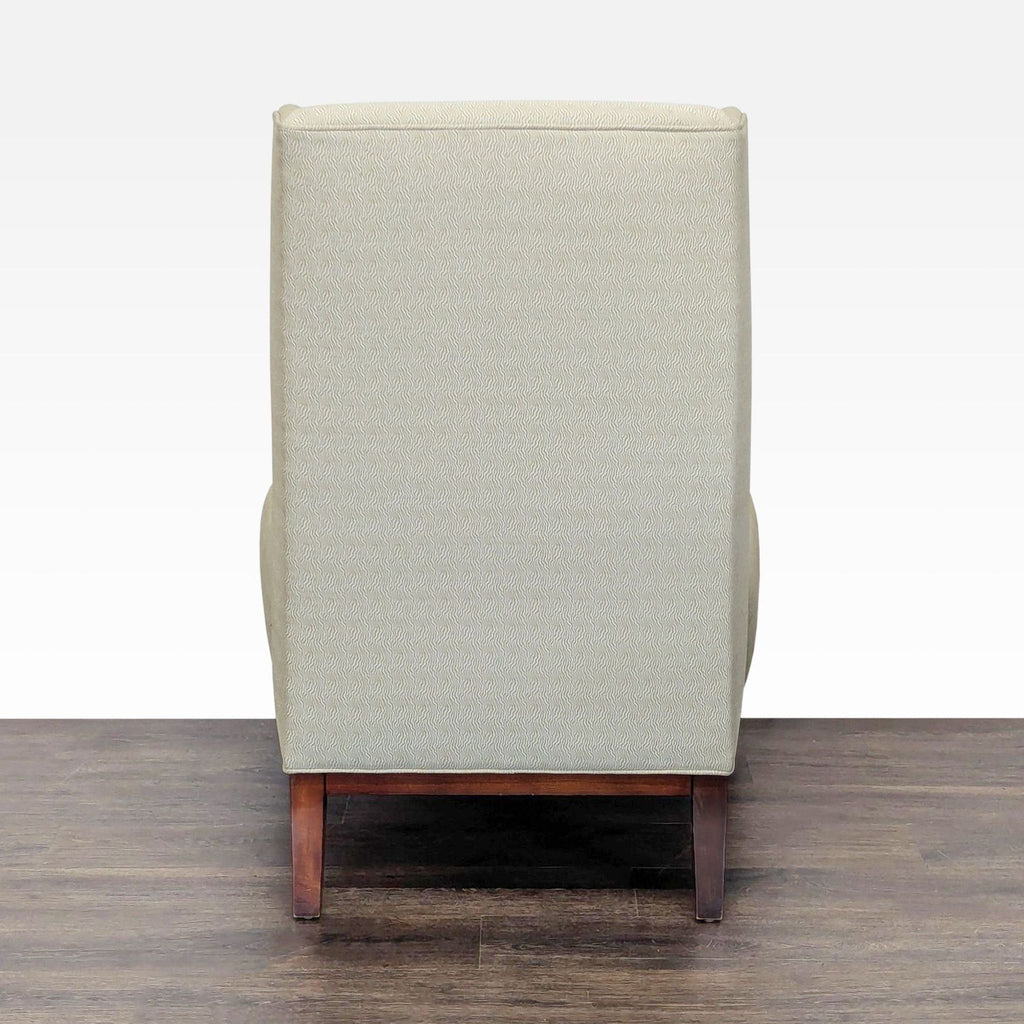 1. Back view of a Reperch lounge chair with light patterned upholstery and wooden legs, placed on dark flooring.