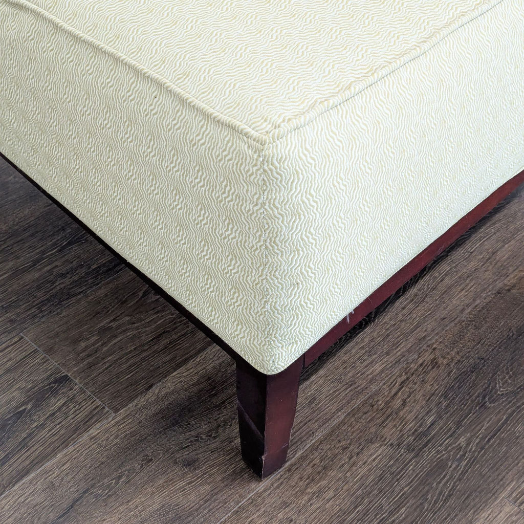 3. Close-up of the Reperch lounge chair’s textured upholstery and wooden leg on a hardwood floor.