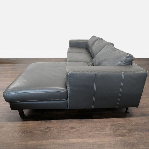 1. Side view of a modern Reperch sectional sofa in dark grey leather with chaise, on a wooden floor.