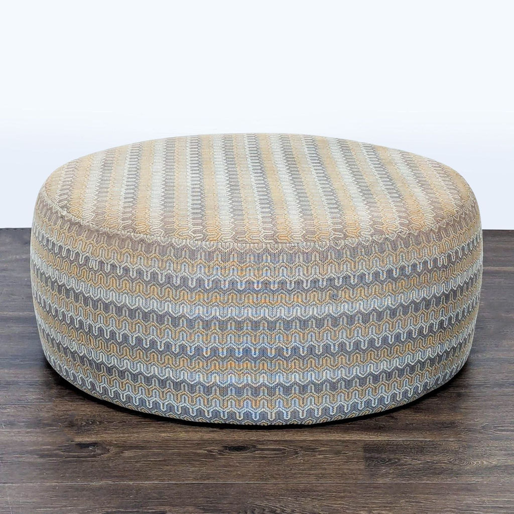 Round ottoman by Room & Board with beige and gray zigzag pattern, pictured on dark wood floor.