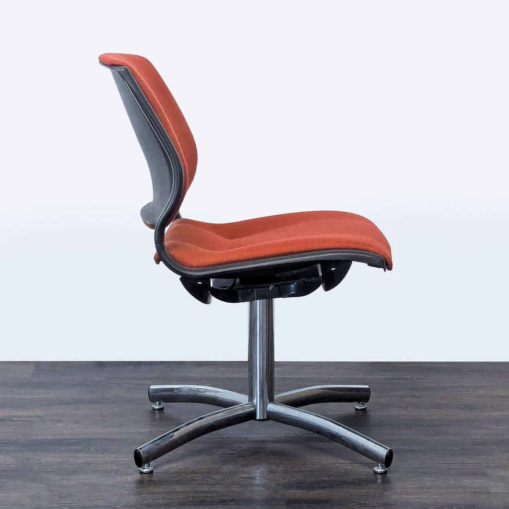 3. Side profile of a Steelcase chair, highlighting orange cushions, contoured design, and metal frame.