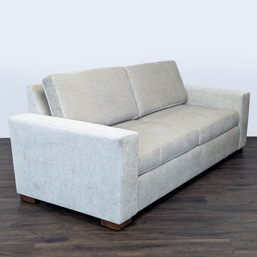 2. Angled side view of a modern Reperch 3-seat sofa in light gray, featuring wide arms and wood feet.