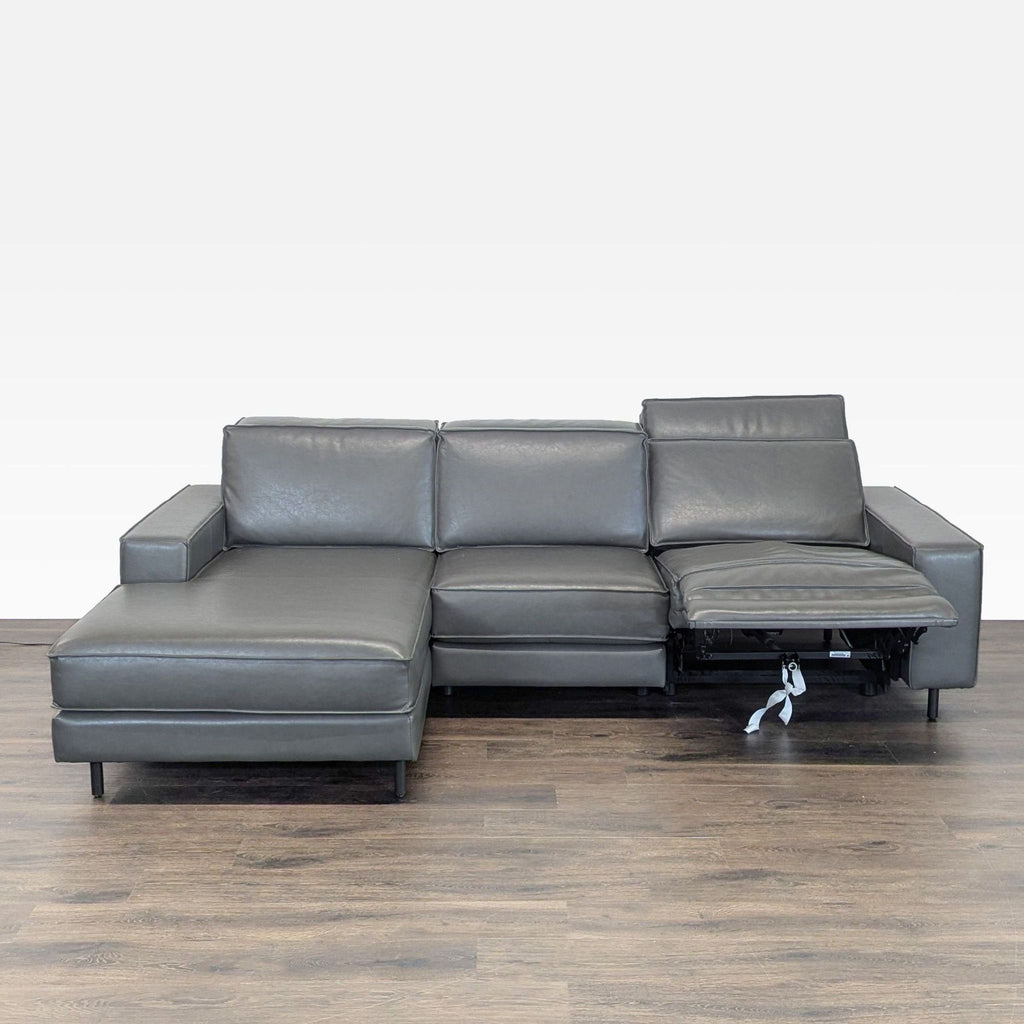 Modern West Elm sectional in sleek gray leather, featuring a left chaise and a reclining right seat.  