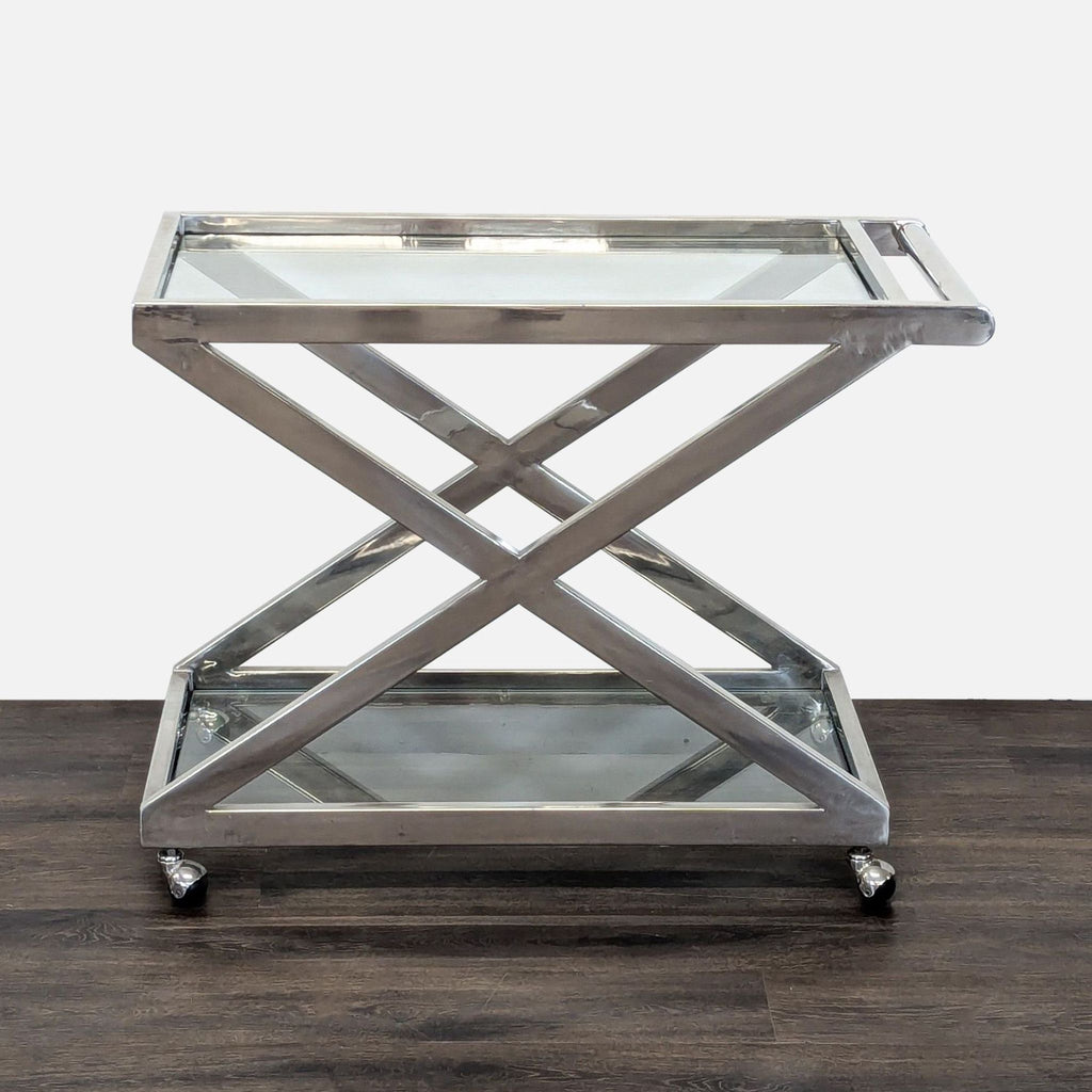 Polished nickel bar cart with X-shaped frame, tempered glass shelves, and round handle on rolling wheels.