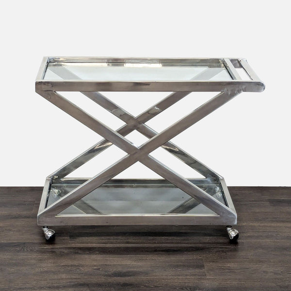 Polished nickel bar cart with X-shaped frame, tempered glass shelves, and round handle on rolling wheels.