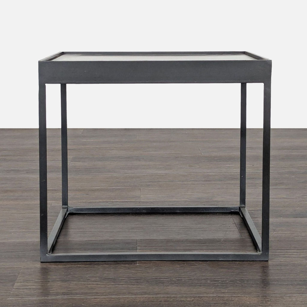 1. Minimalist square metal side table with thin black frame, shown on a dark wooden floor, straight-on view.  
