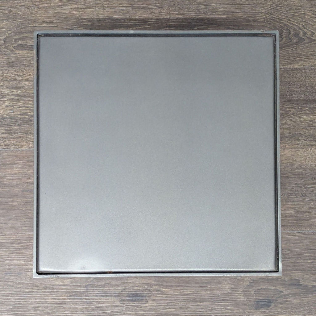 3. Overhead view of a square black metal side table top, showcasing its clean and solid surface design.