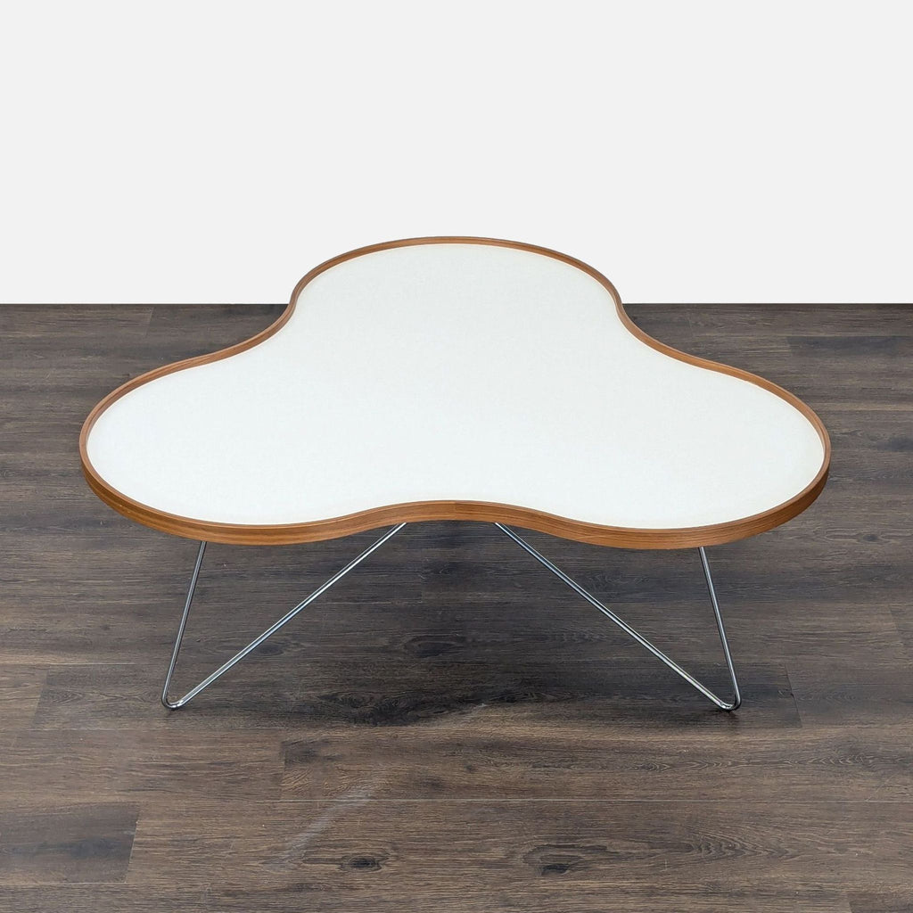 Swedese coffee table featuring a rounded white laminate surface, wooden edge, and slender chrome base, by Christine Schwarzer.