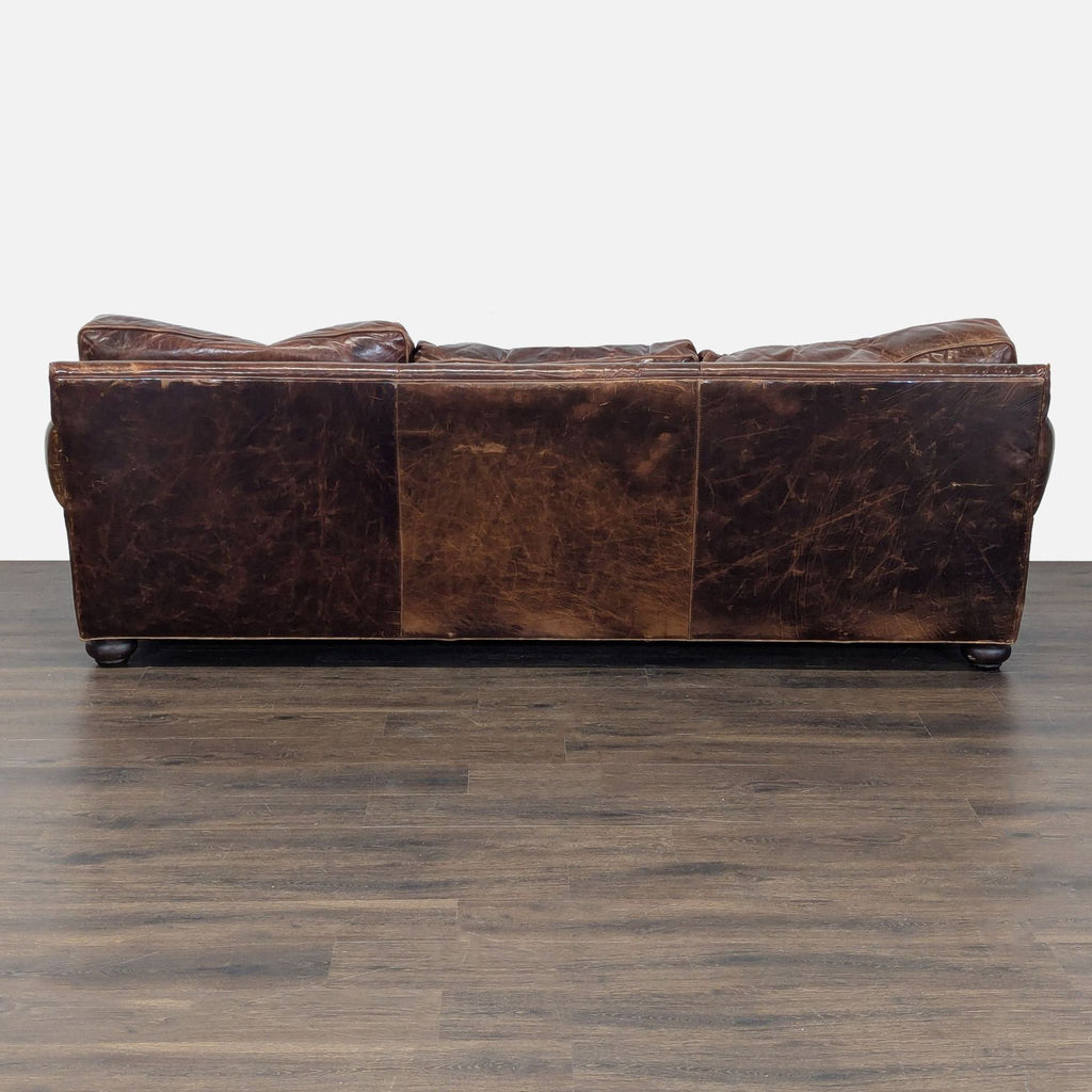 Back view of a weathered brown leather Restoration Hardware 3-seat sofa with visible creasing and vintage character.