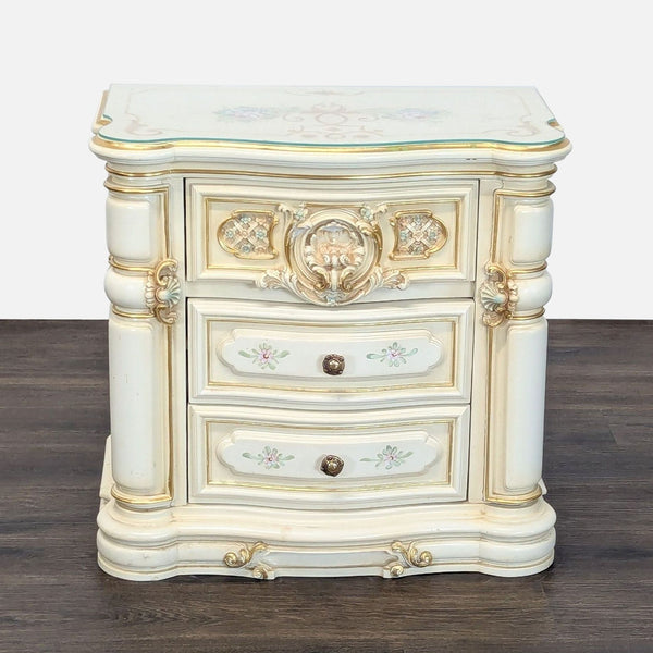 Ornate end table with heavy carvings, gold accents, and a protective glass top.