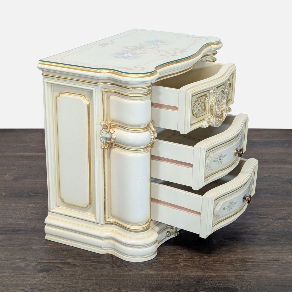 Decorative end table featuring intricate gold detailing and a glass-covered surface.