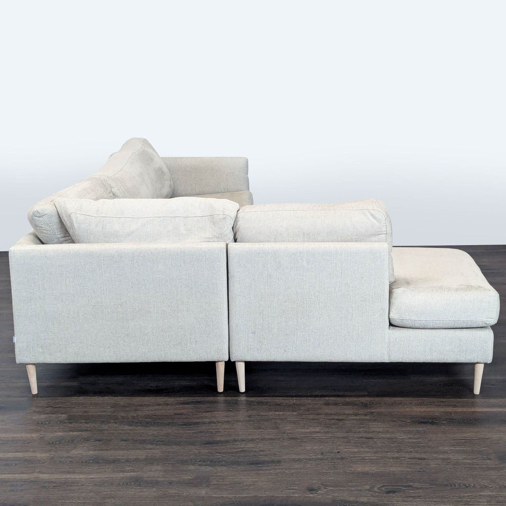 Cream BoConcept sectional sofa with chaise lounge, supportive back cushions, and sleek wooden legs for a modern look.