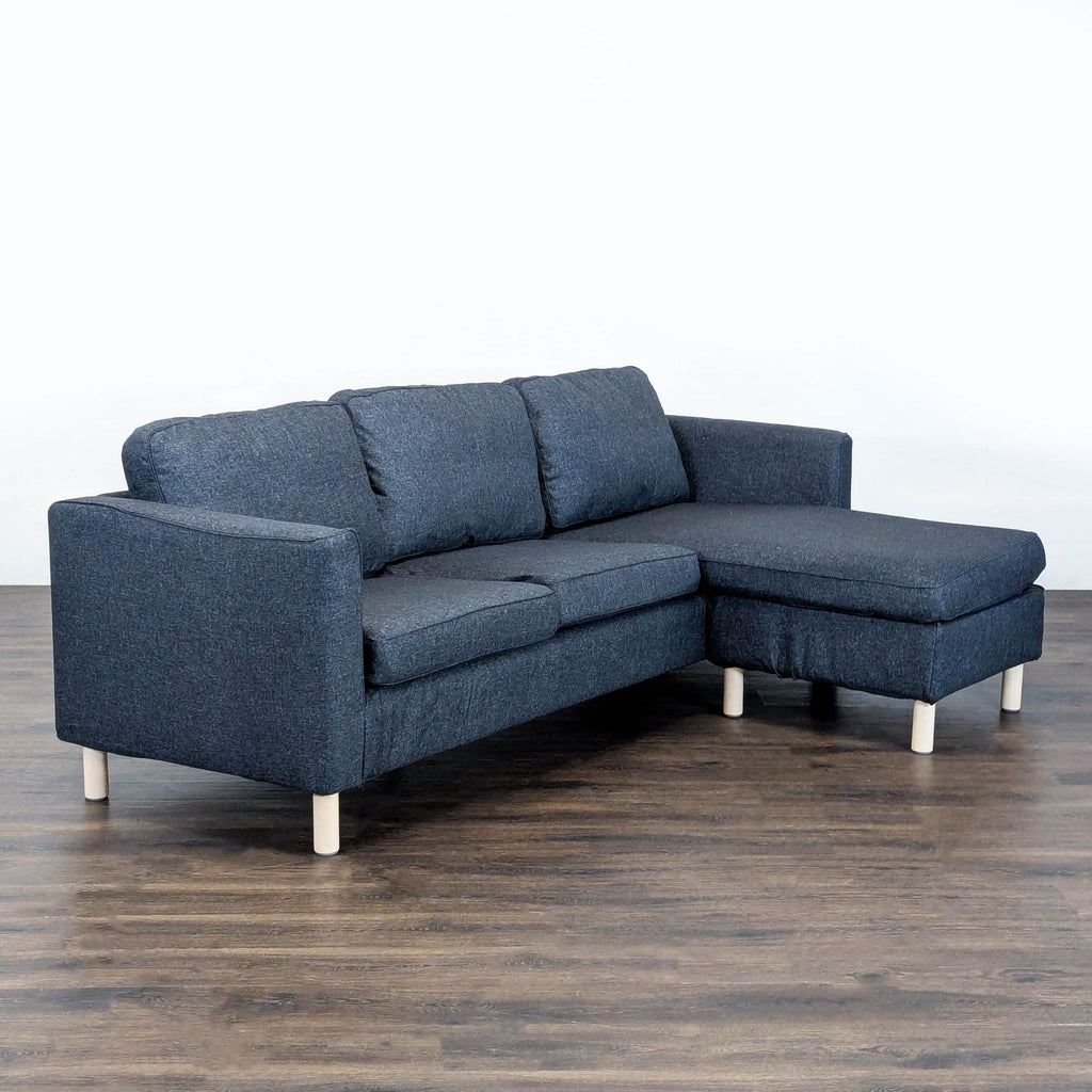 Ikea sectional sofa with dark blue upholstery, right-side chaise, and light wood legs; ideal for small living spaces.