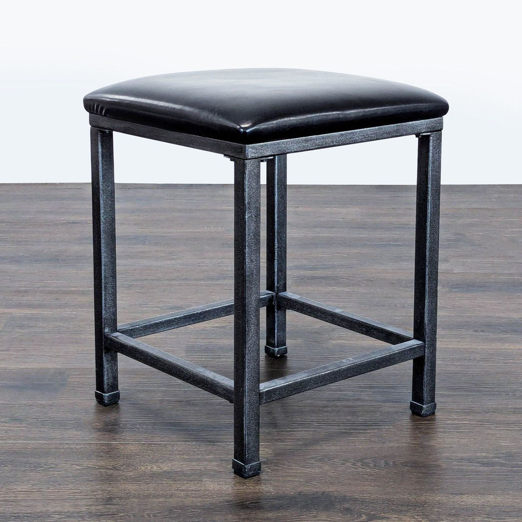 3. Angled view of a square black leather stool with a metal frame, suitable for seating or accent use.