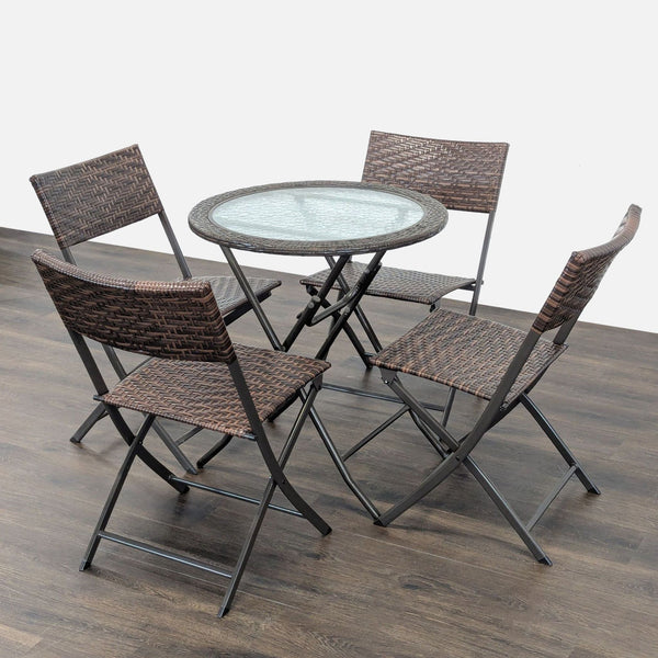 Round glass-top table with four matching rattan-style folding chairs, ideal for patios or balconies.