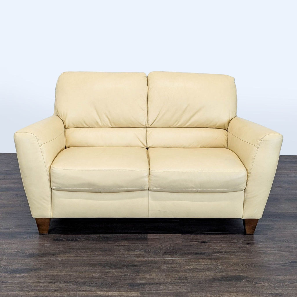 Natuzzi loveseat with soft leather, wooden legs, plush cushions, and sleek modern design, seats two comfortably.