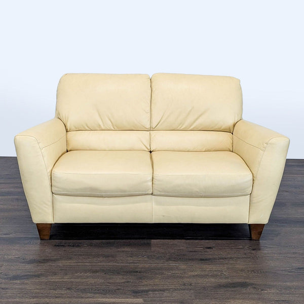 Natuzzi loveseat with soft leather, wooden legs, plush cushions, and sleek modern design, seats two comfortably.