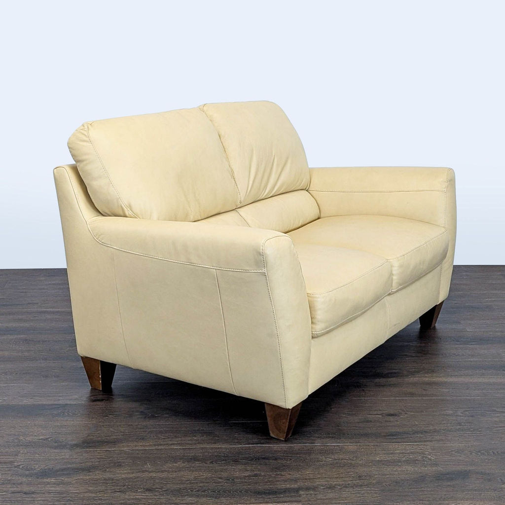 Contemporary loveseat by Natuzzi with cushioned leather upholstery and elegant wooden legs, ideal for living rooms.