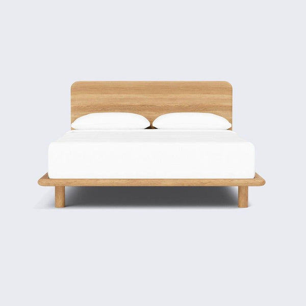 Modern oak bed frame by The Citizenry, featuring clean lines and rounded edges for a stylish, minimalist bedroom look.  