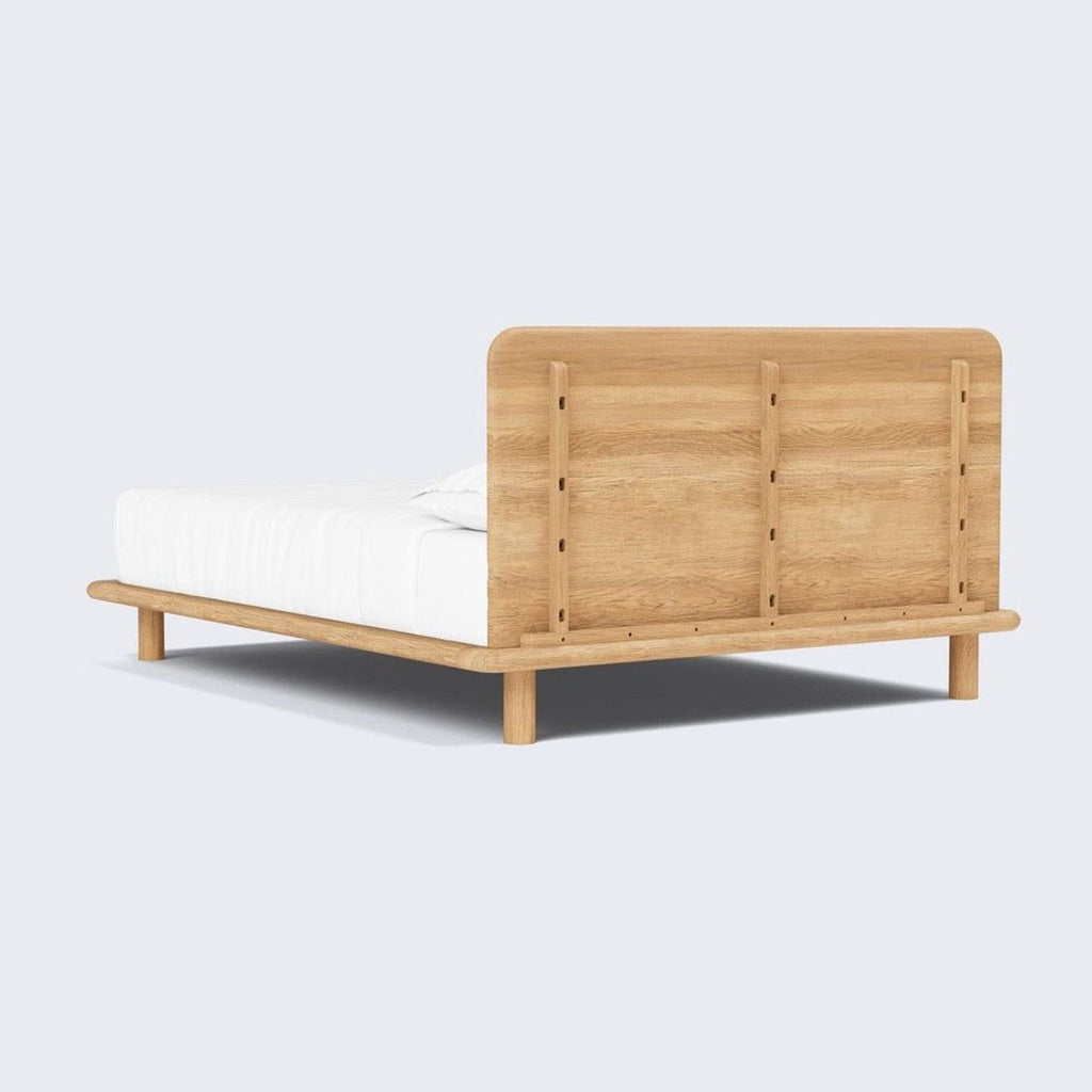 The Citizenry’s oak bed frame with simple design and strong support, blending timeless style with functional comfort.