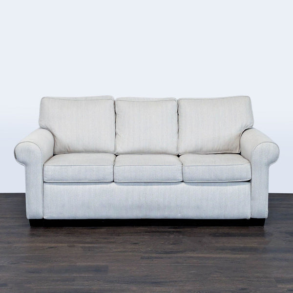 Modern West Elm sleeper sofa with neutral fabric, rolled arms, and three supportive cushions, converts easily to a bed.
