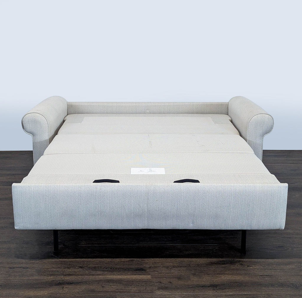 Sleek West Elm sofa in neutral upholstery, featuring rolled arms and cushions, doubles as a comfy guest bed.